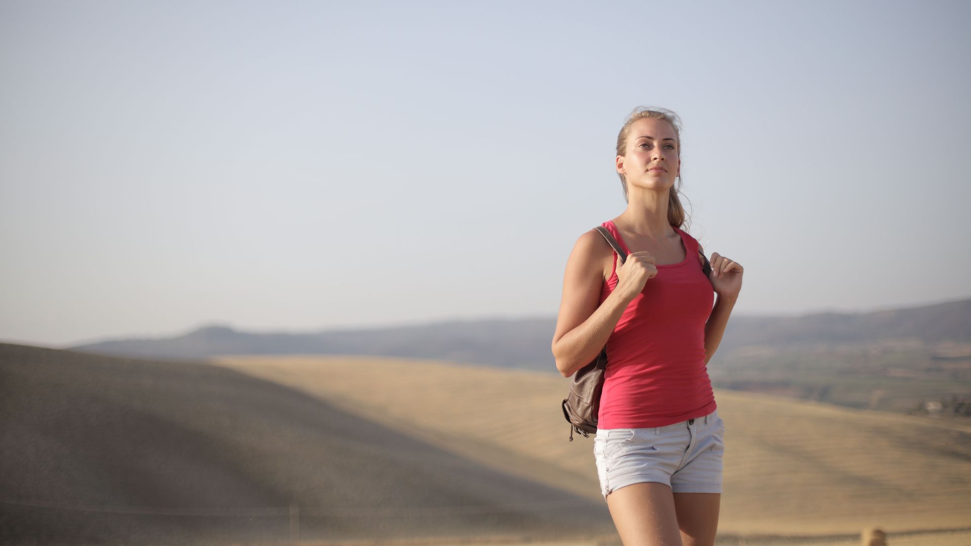 Confident female hiker exploring scenic rolling hills in casual summer attire.