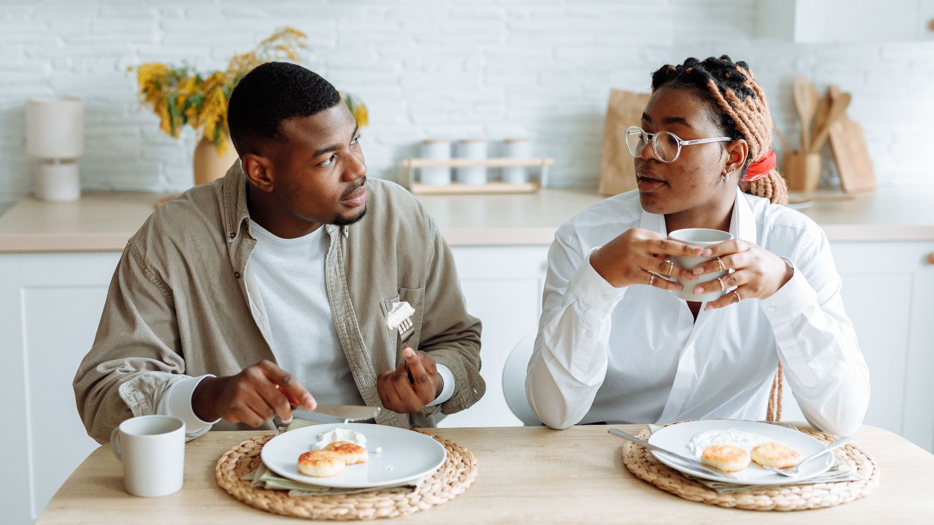 A couple having a relaxed breakfast at a cozy indoor setting, enjoying pastries and coffee.