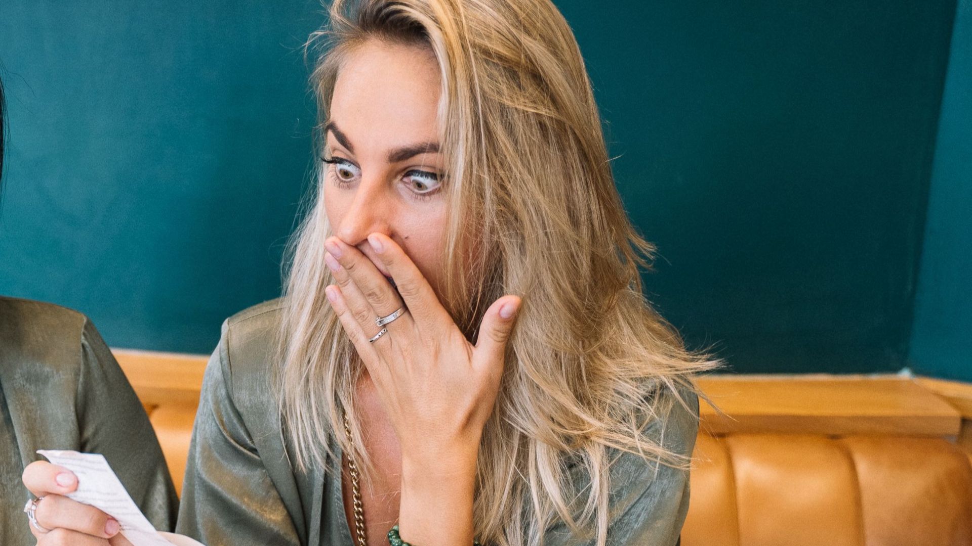 Two women express surprise while reviewing a restaurant bill in a casual setting.