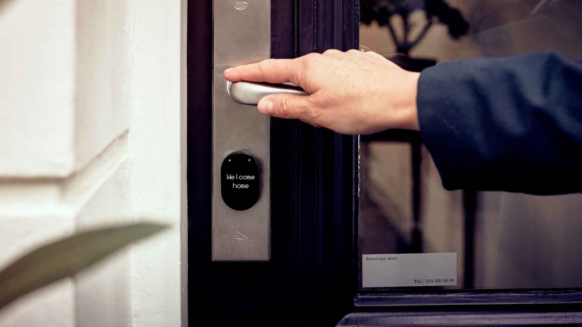 A hand opening a smart home door with digital access panel, conveying security and technology.