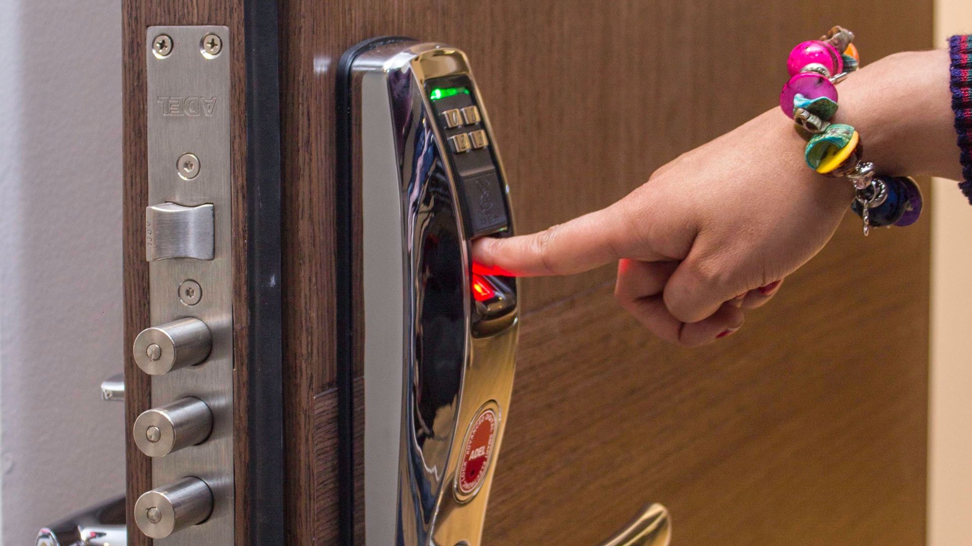 A hand using fingerprint access on a digital security door lock, enhancing safety.