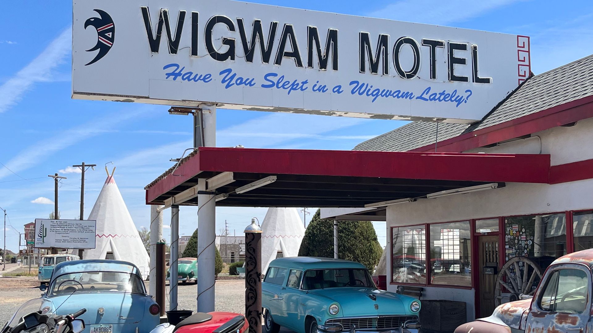 Vintage cars and Wigwam Motel sign in Holbrook, AZ, under a clear sky.