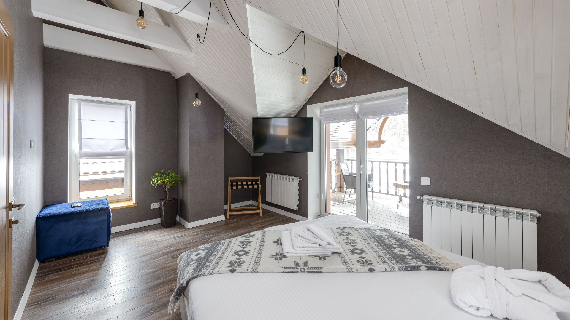 A modern bedroom with a large bed, balcony access, and stylish lighting.