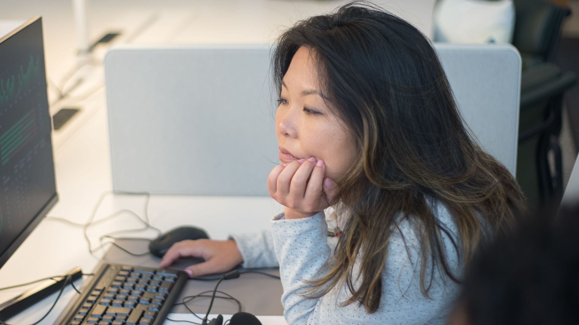 Woman intently viewing a computer monitor in a modern office environment.