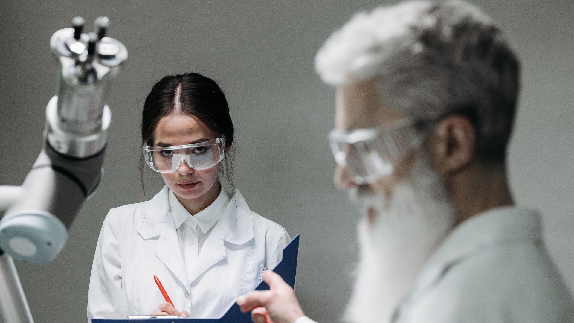 Researchers in lab coats interacting with advanced robotic arm technology.