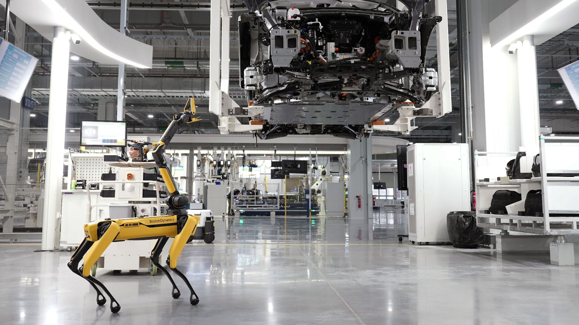 A robotic dog oversees an automated car assembly in a high-tech factory setting.