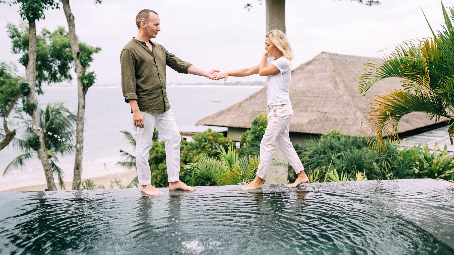 Couple holding hands and enjoying a tropical vacation by the poolside.