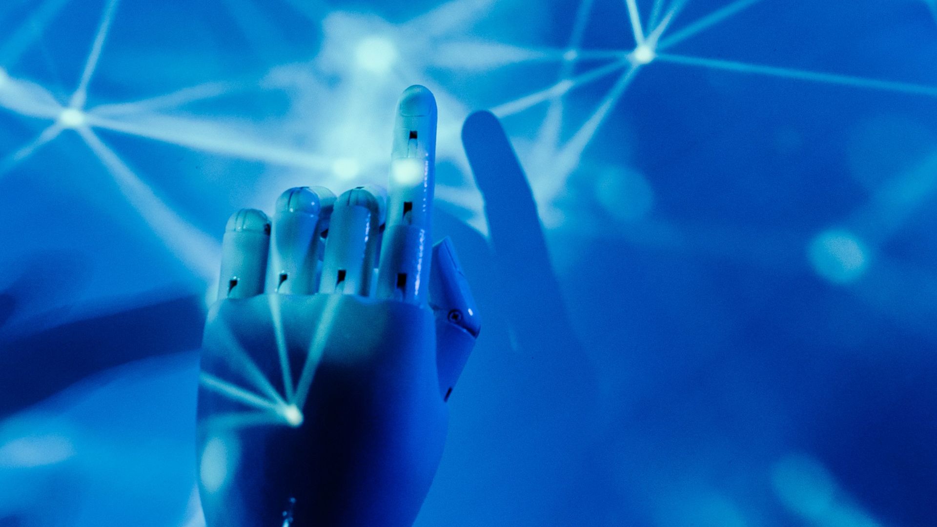 Futuristic robotic hand touching a digital network on a blue background.