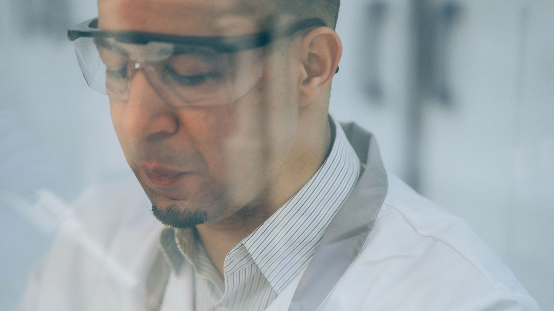 Man in lab coat conducting scientific research in a controlled lab environment.