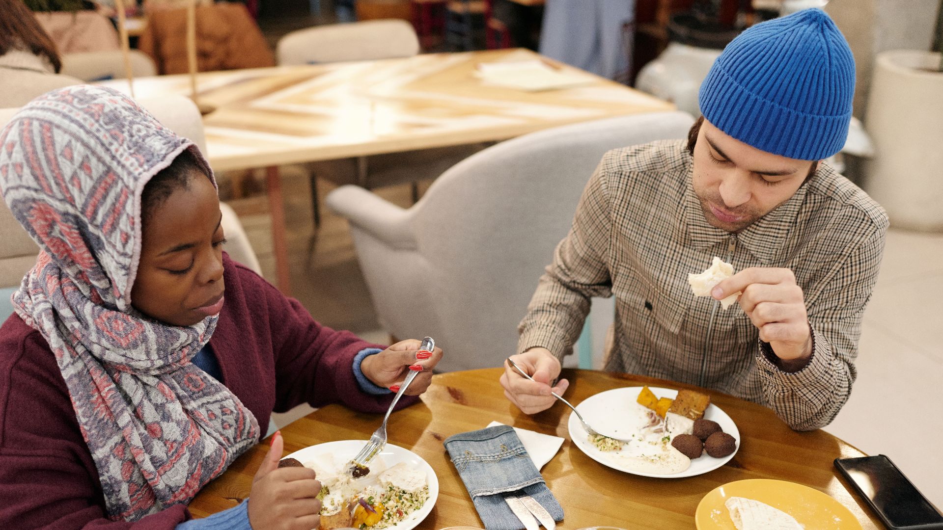 A multiethnic couple dining indoors, enjoying a Middle Eastern meal.
