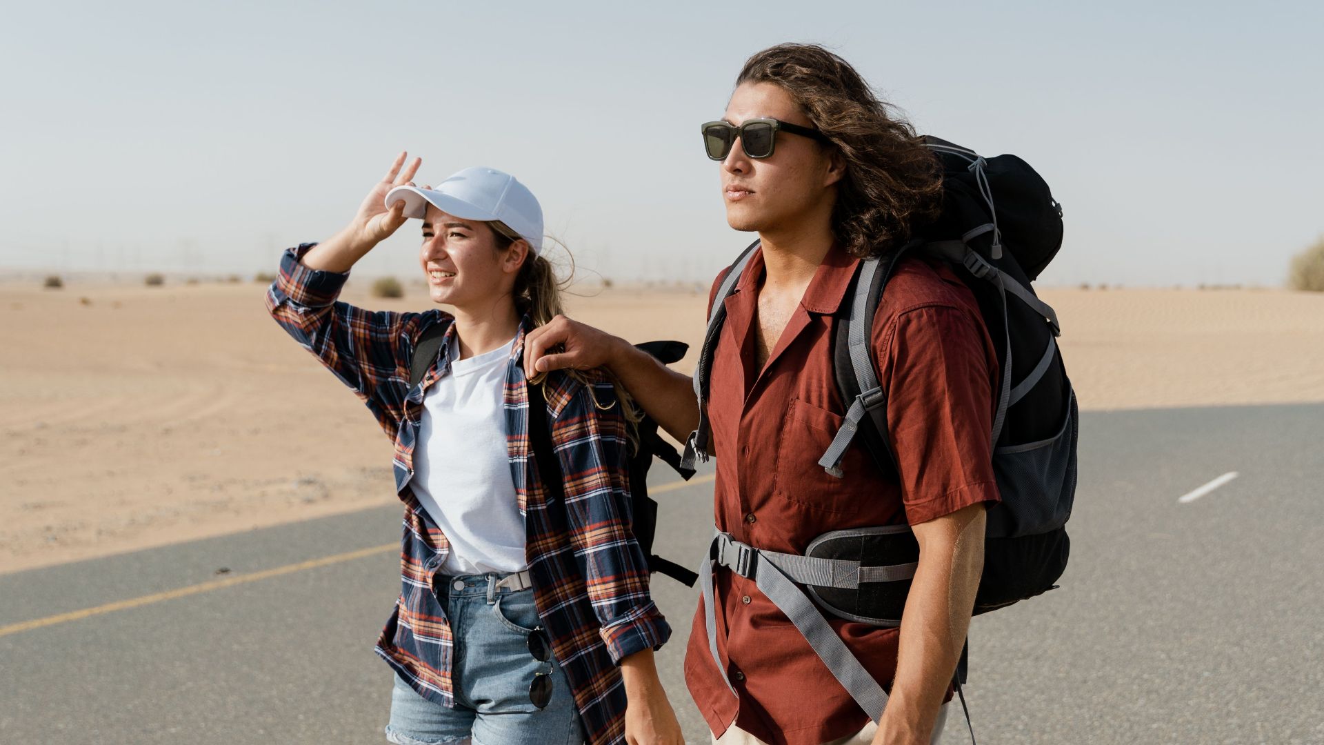 Young couple backpacking through a desert road, capturing wanderlust and exploration.