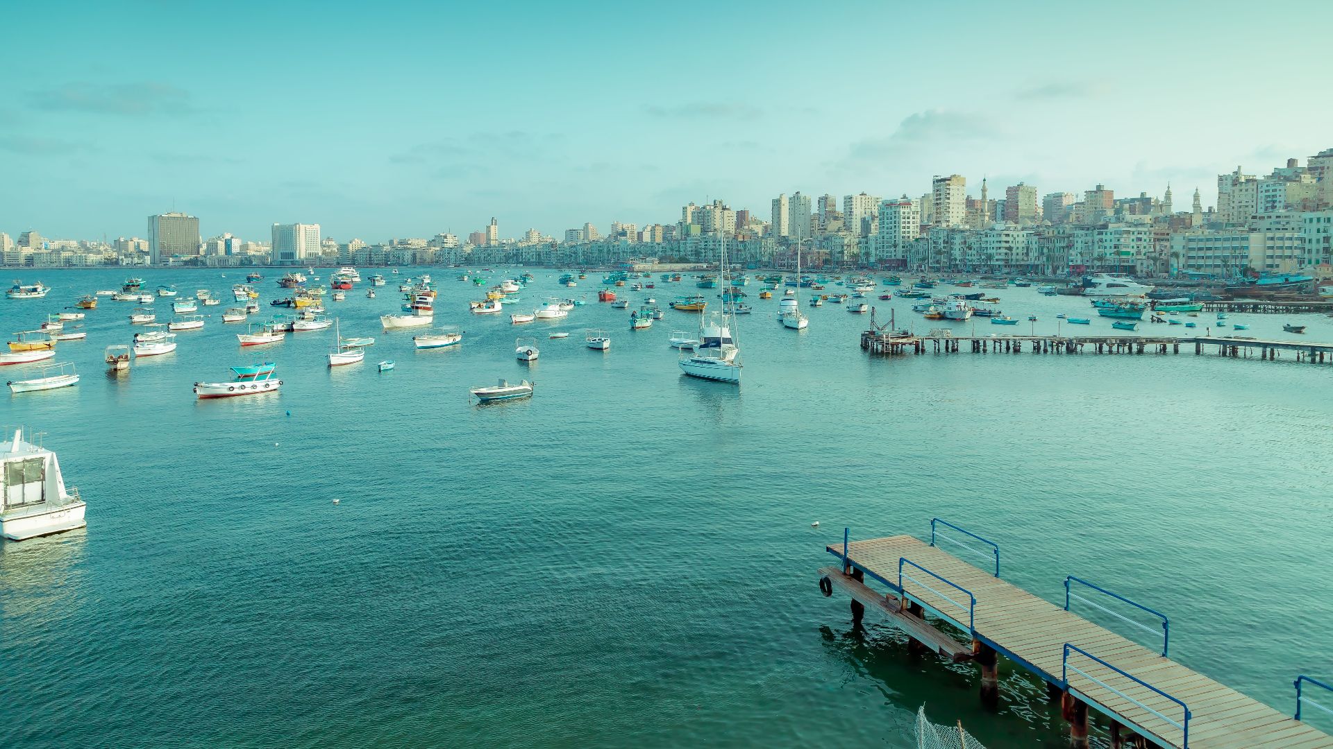 A stunning view of Alexandria's harbor featuring boats, piers, and the city skyline.