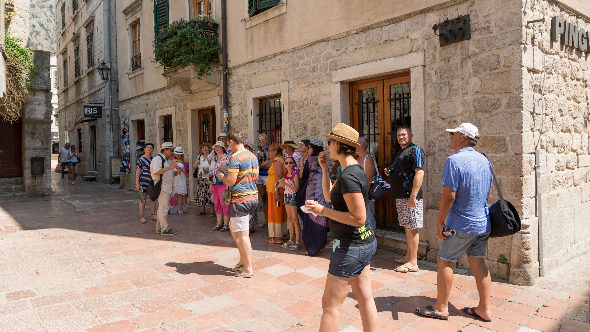 Tourists explore historical European town's vibrant streets on a sunny day, capturing local architecture.