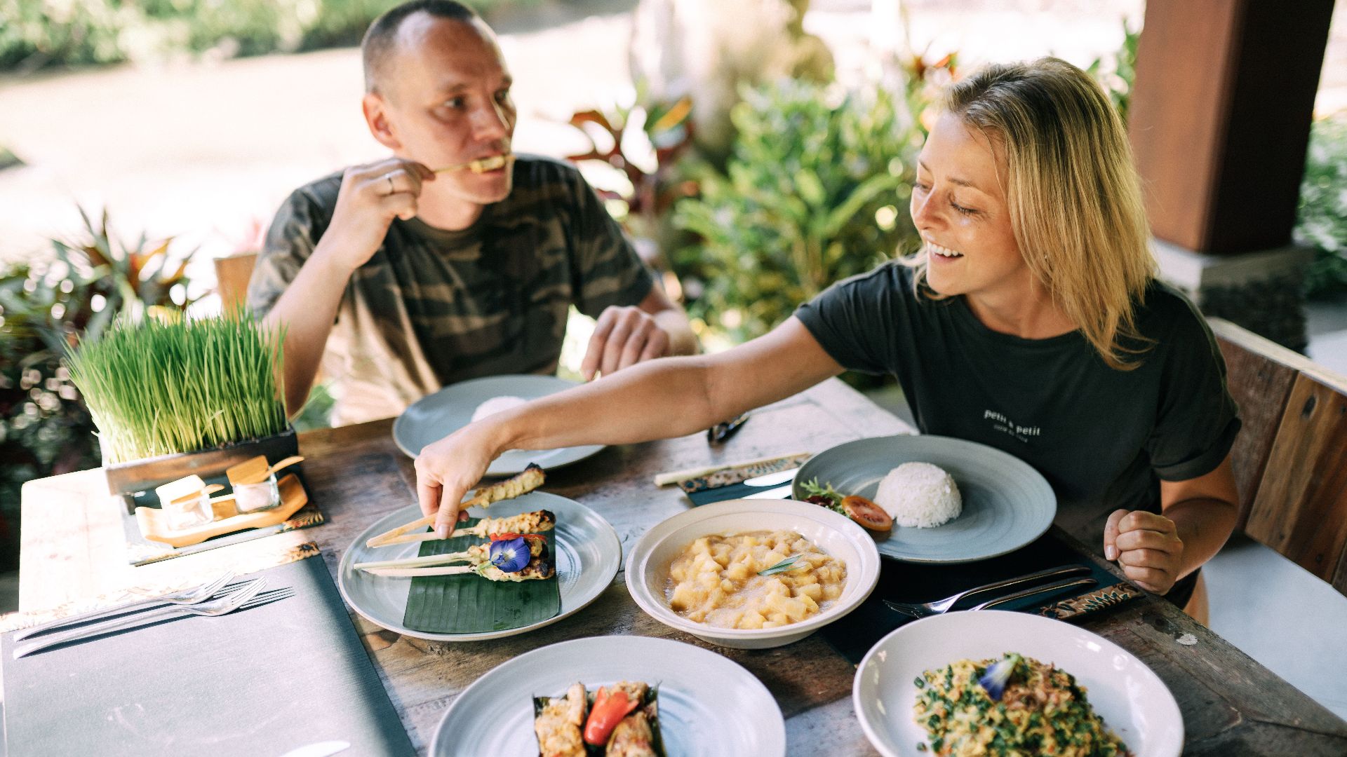 A couple enjoying a variety of Asian dishes outdoors at a cozy table setting.