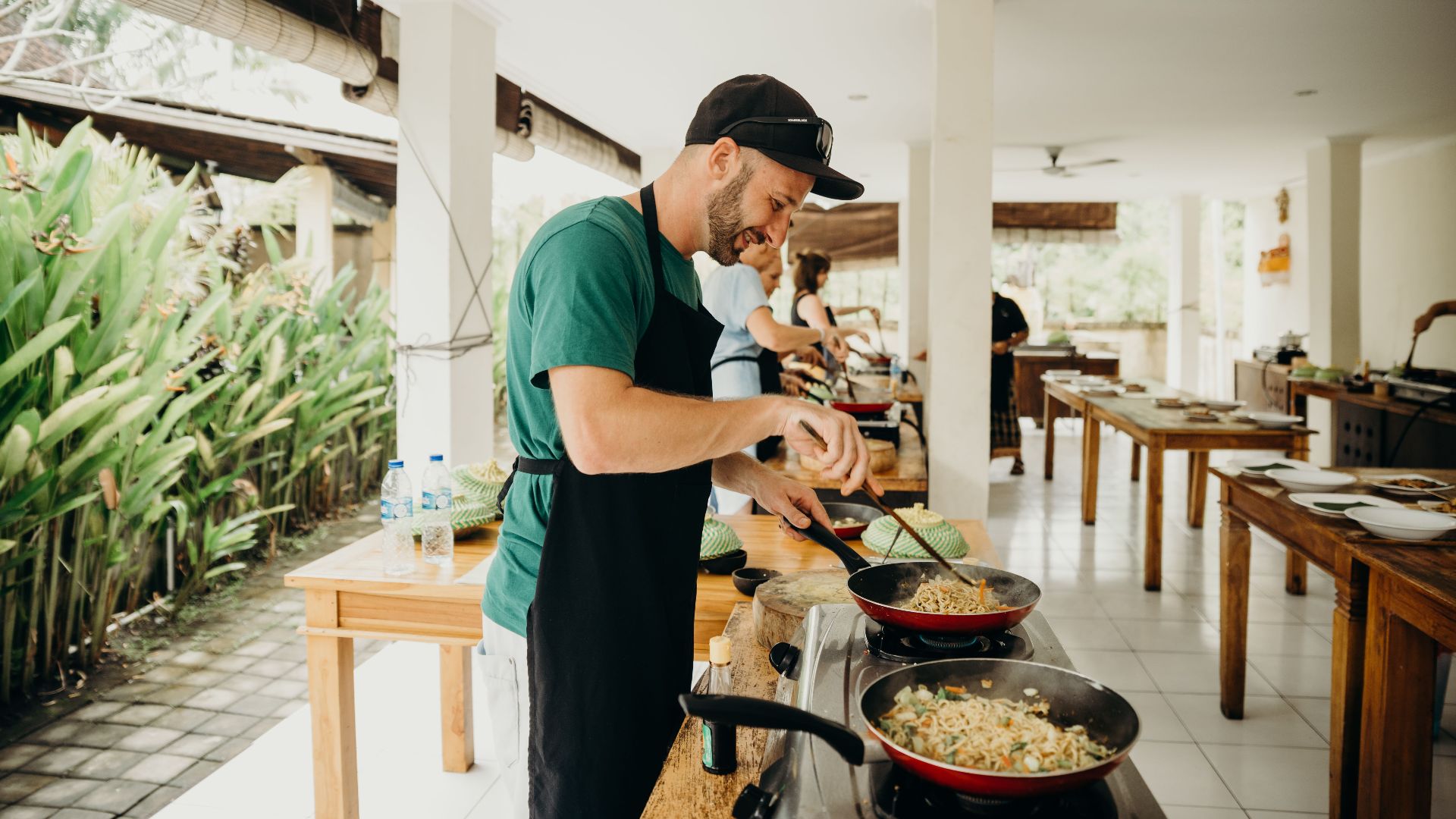 A chef prepares a meal in an open-air kitchen setting in Bali, Indonesia.