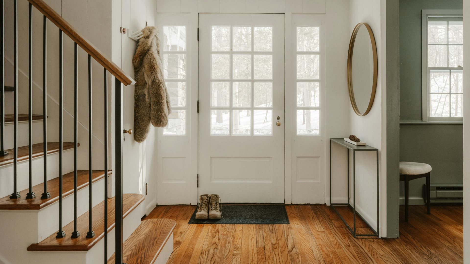 A cozy entryway with wooden stairs and a glass door.