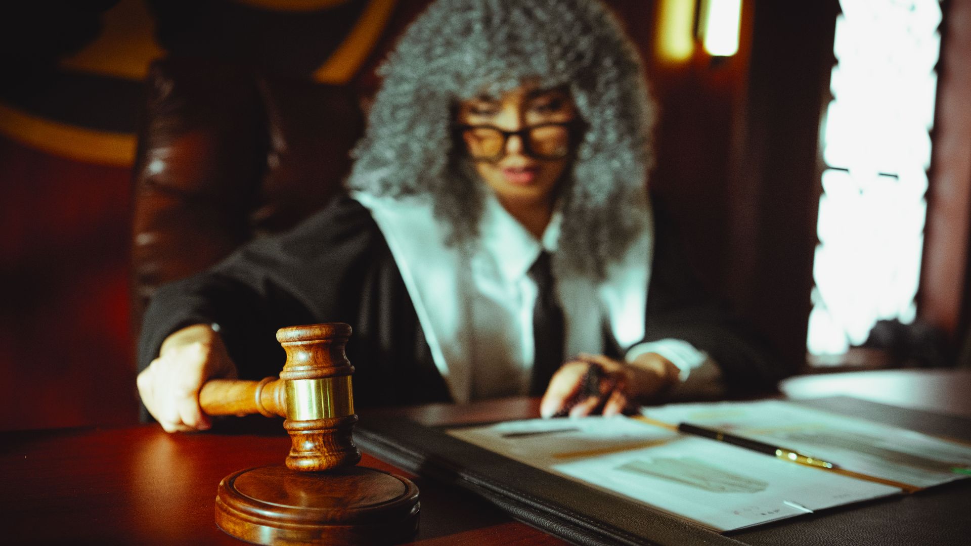 Female judge in a courtroom setting, focusing on legal documents with a gavel.