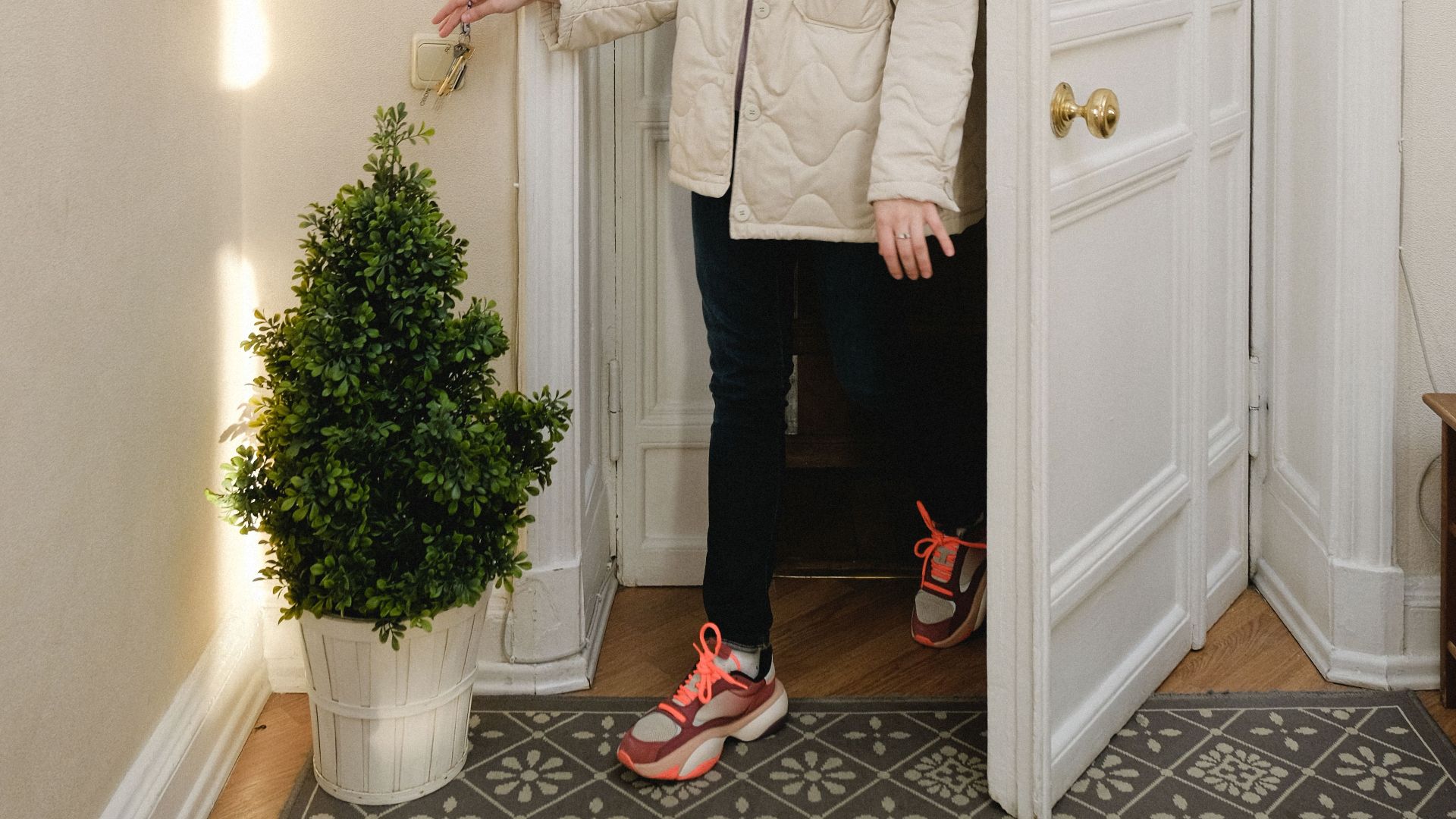 A woman exits through a stylish wooden doorway. Cozy indoor setting with natural light.