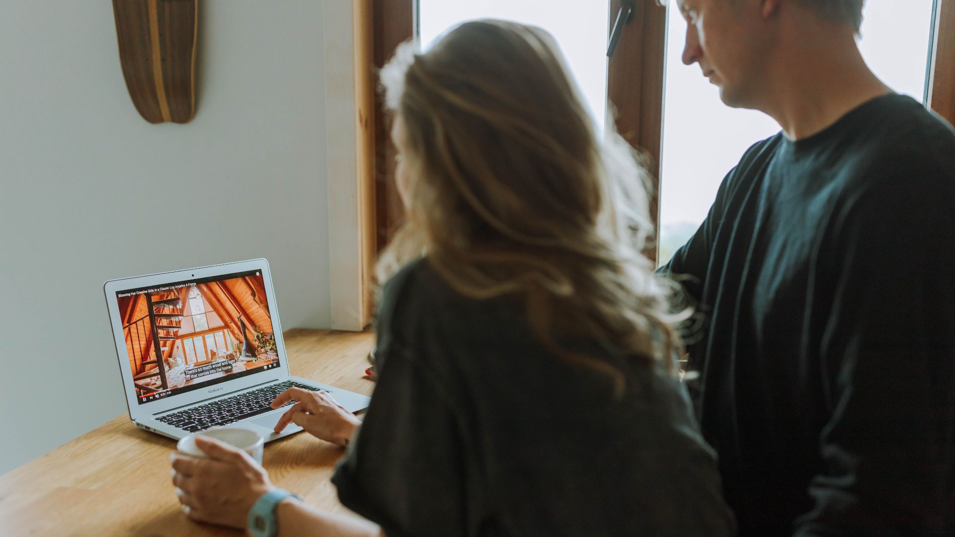 A couple viewing home interior design on a laptop while enjoying coffee together indoors.