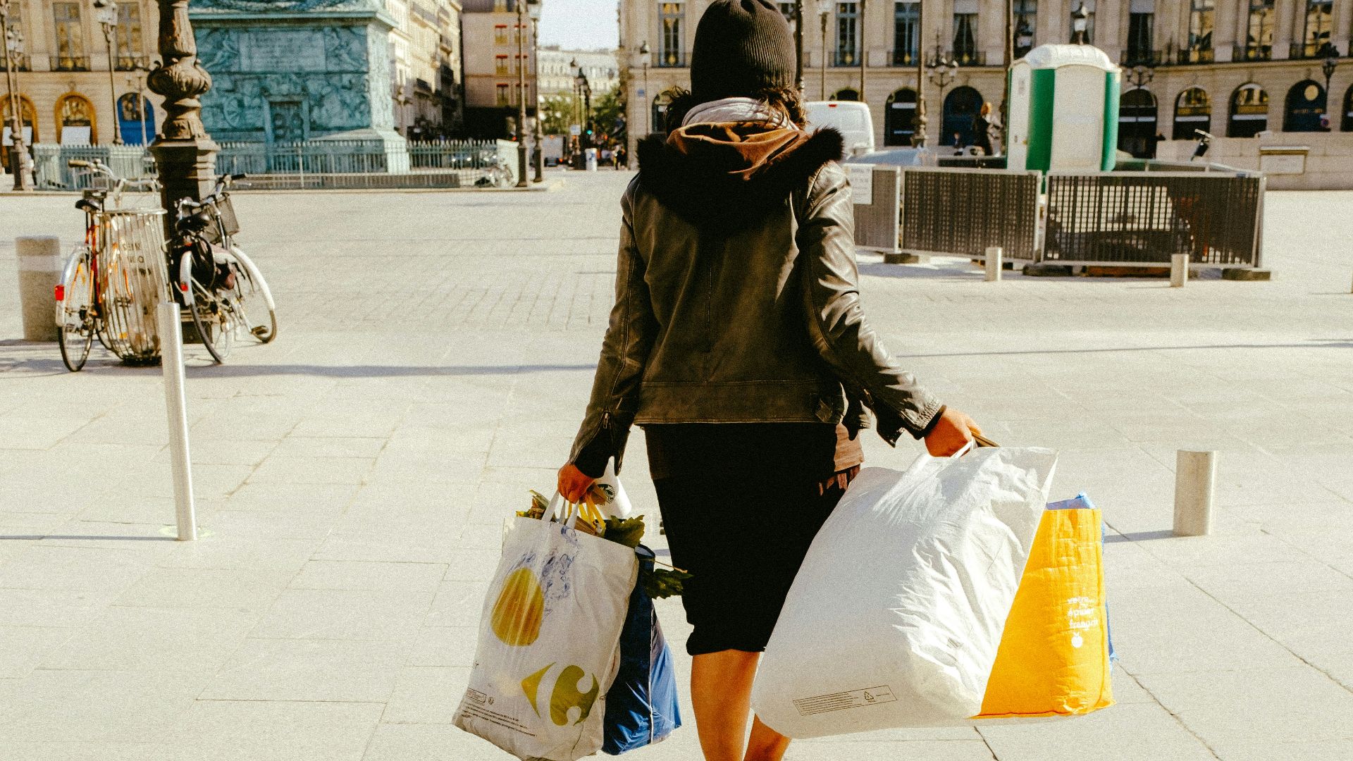 woman in black jacket and white skirt walking on sidewalk during daytime