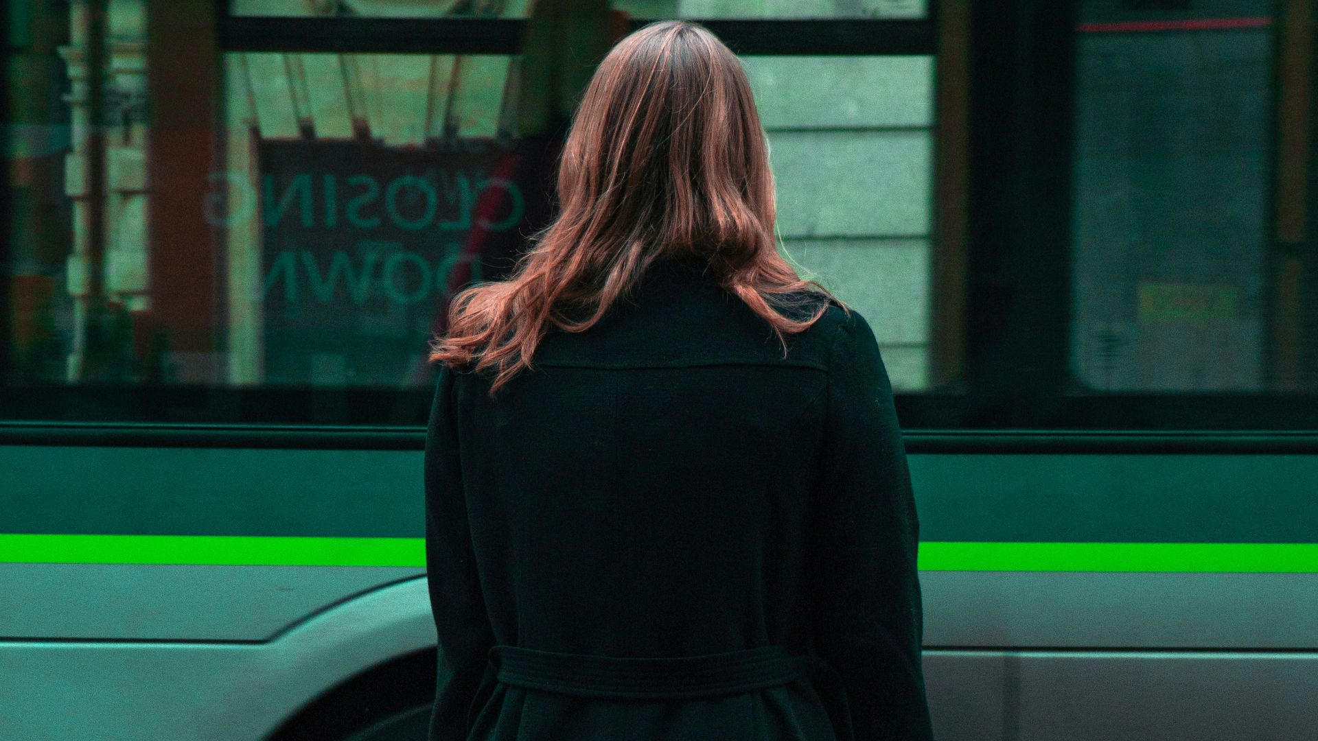 woman in black coat standing on sidewalk during daytime