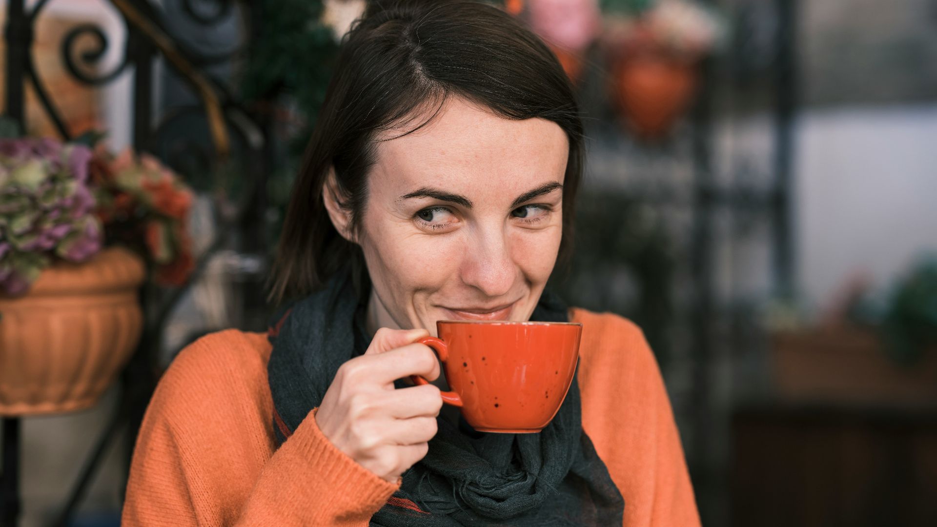 a woman holding a cup of coffee and smiling