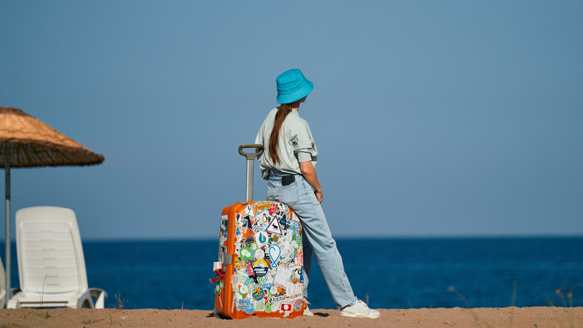 a woman standing on a beach with a suitcase
