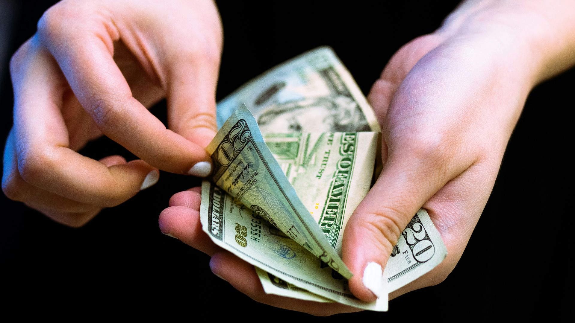 person holding fan of 100 us dollar bill