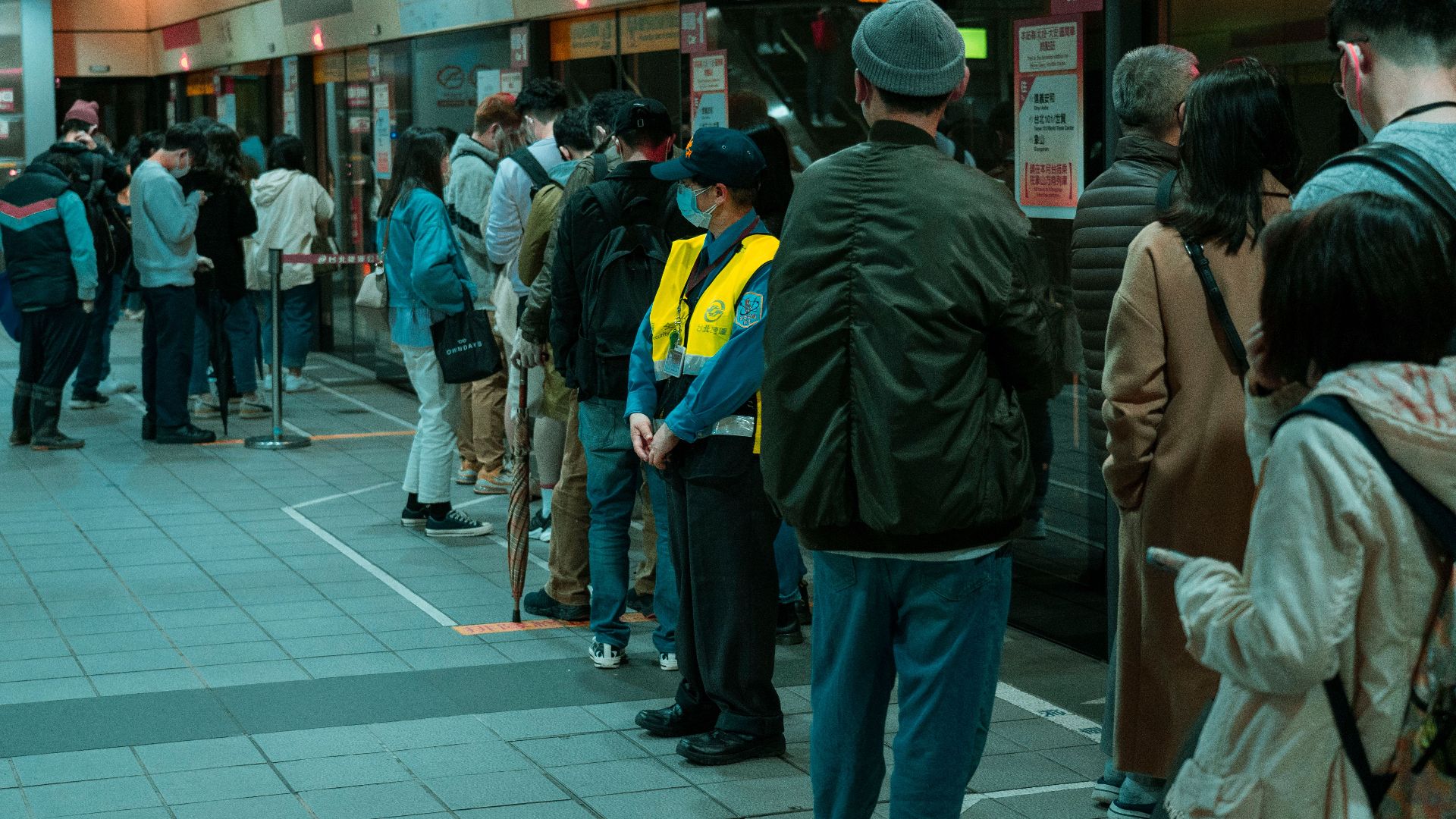 Commuters line up at a subway station platform, showcasing public transportation dynamics.