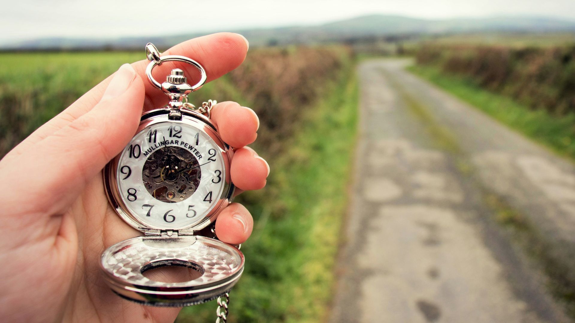 person holding silver-colored pocket watch