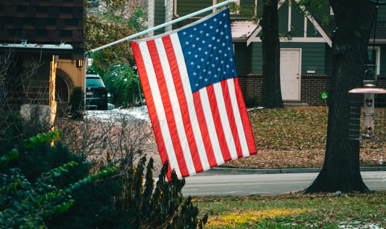 American flag flying proudly in a peaceful suburban neighborhood street
