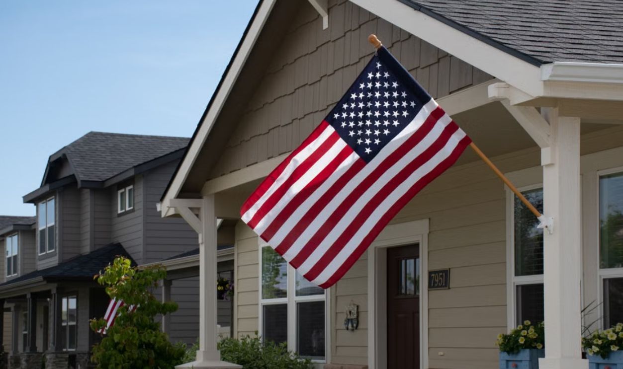 A vibrant American flag displayed outside a stylish suburban house in daylight