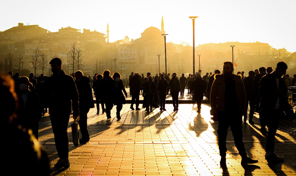 Silhouetted people walking through a sunlit park in Istanbul, capturing the vibrant city atmosphere