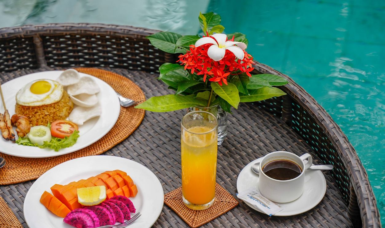 A vibrant poolside breakfast in Bali with tropical fruits, rice dish, and fresh coffee