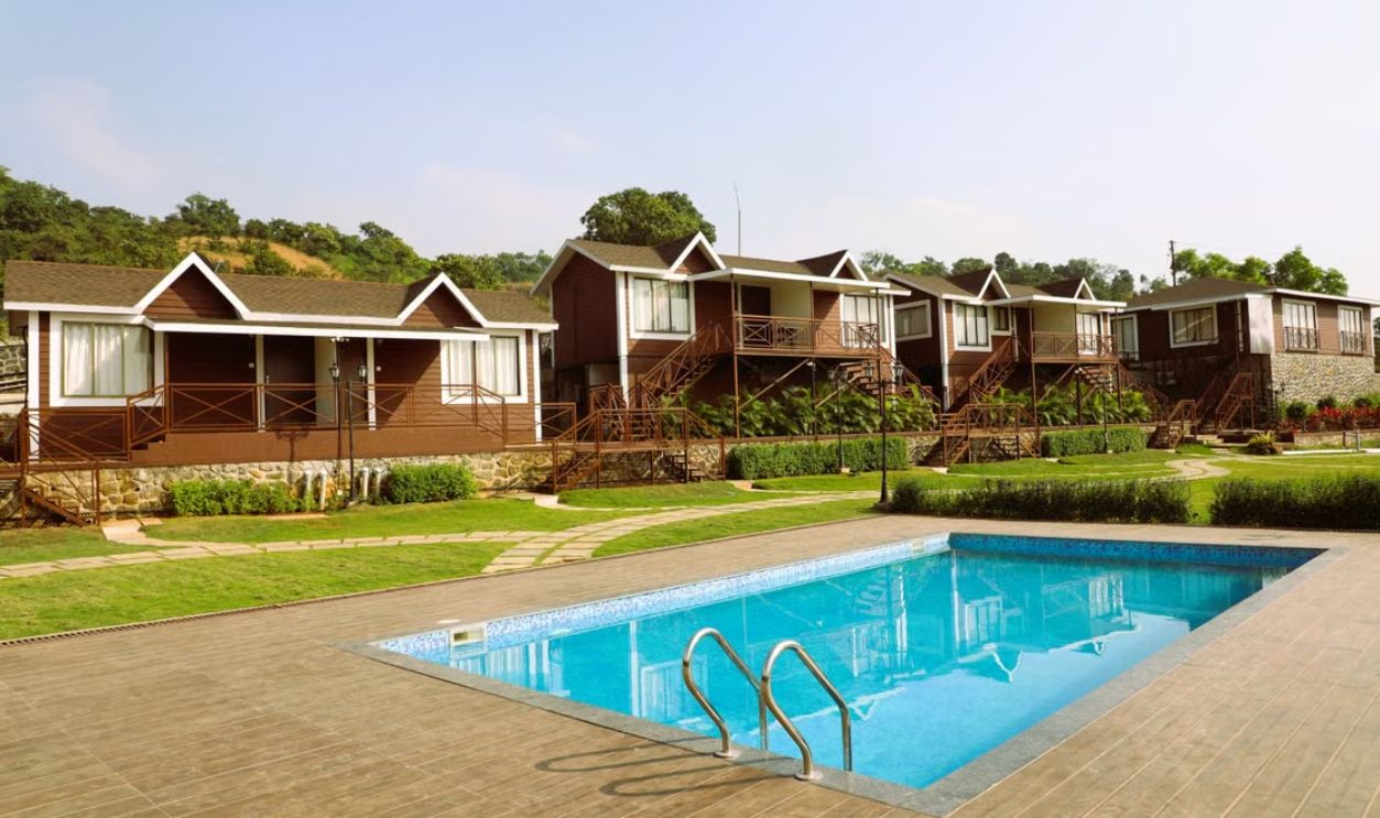 Rustic wooden cabins with a pool and lush surroundings in a serene setting.