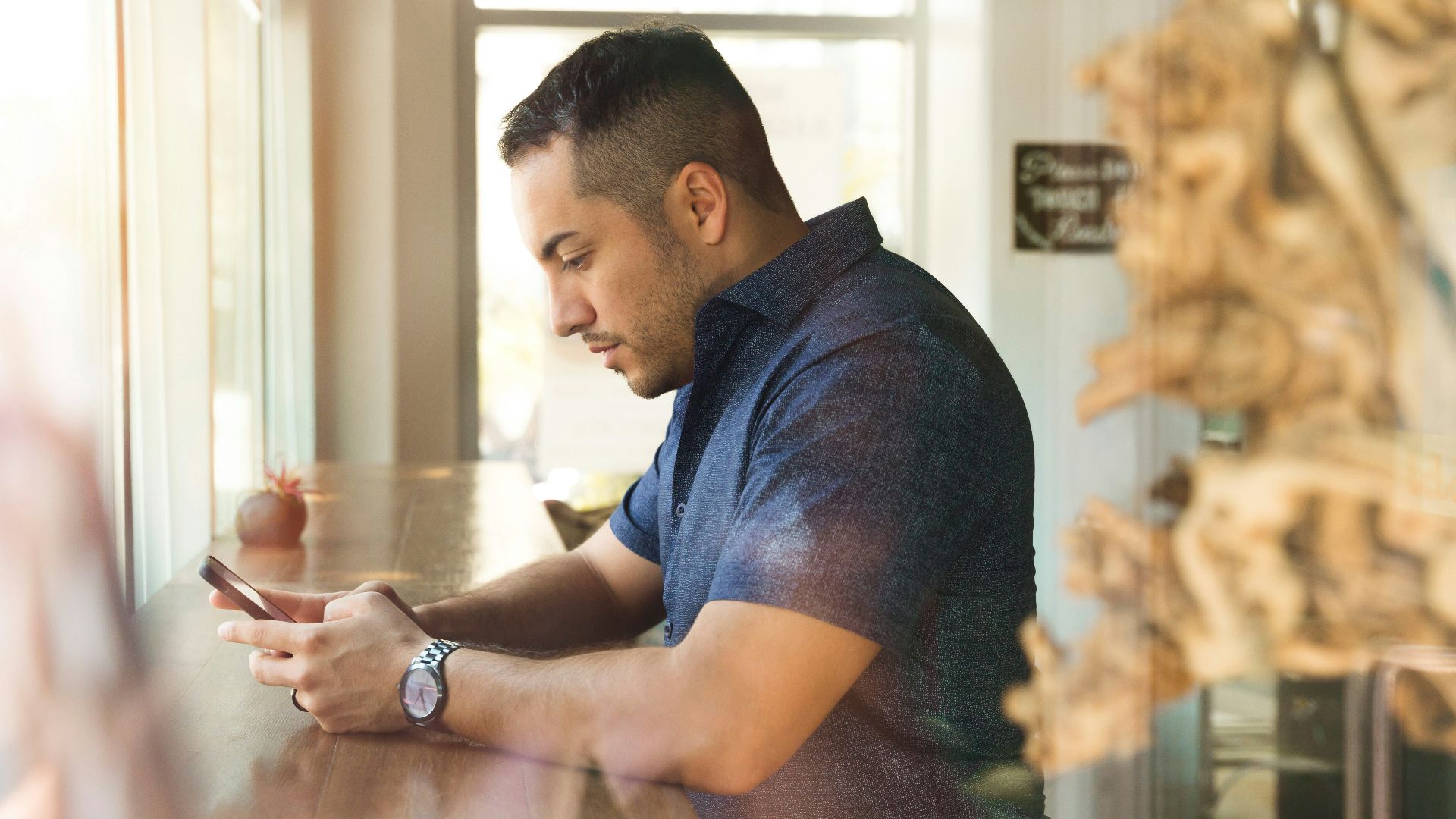 man in black button-up shirt holding smartphone