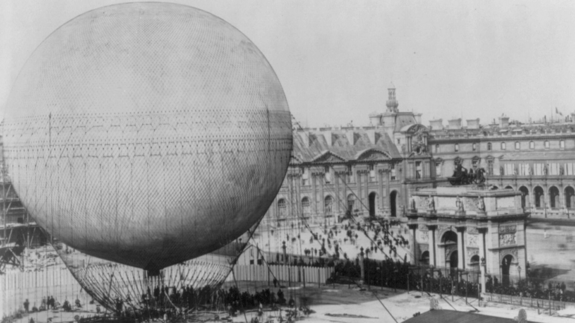 Henry Gifford's (Henri Giffard's) en:balloon before ascension, 1878. Photo taken from the ruins of the Tuileries Palace, showing the Tuileries courtyard, the Arc de Triomphe du Carrousel, the Place du Carrousel and the north wing of the Louvre Palace.