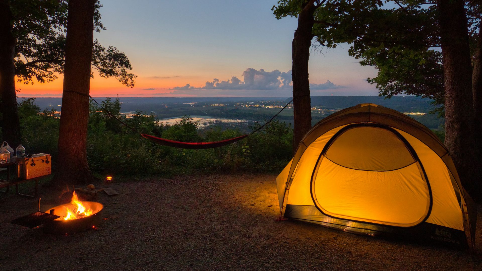 a tent set up in the woods at sunset