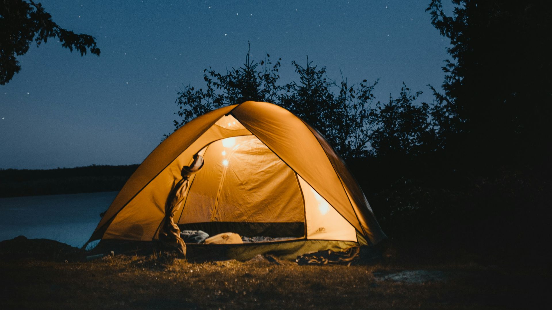 brown dome tent near trees at night