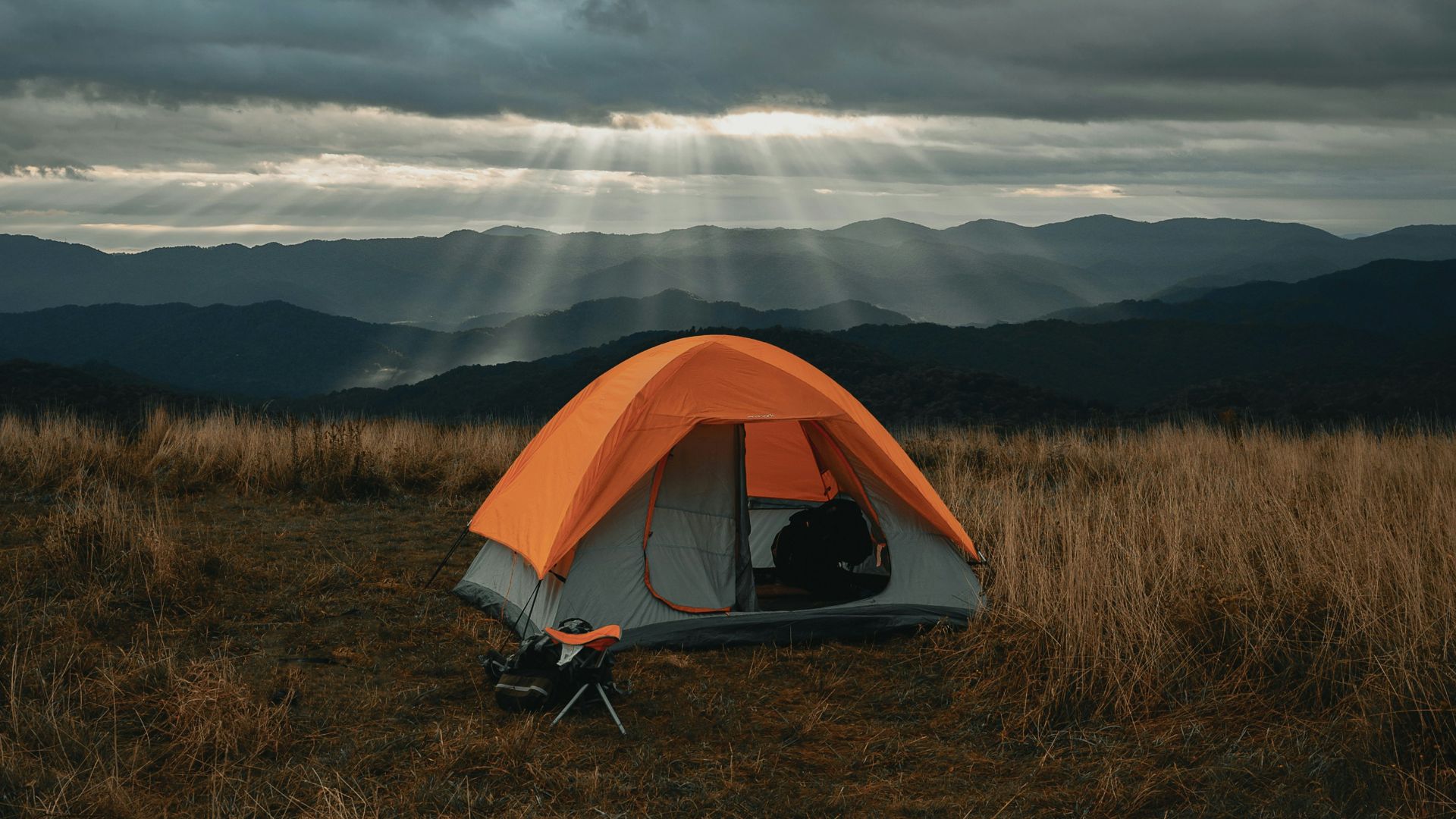 set-up gray and orange tent on brown field under cloudy sky