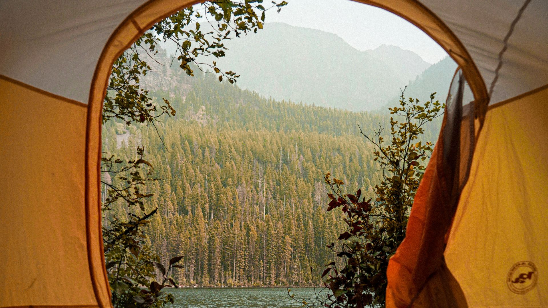 person lying on orange and white tent near body of water during daytime