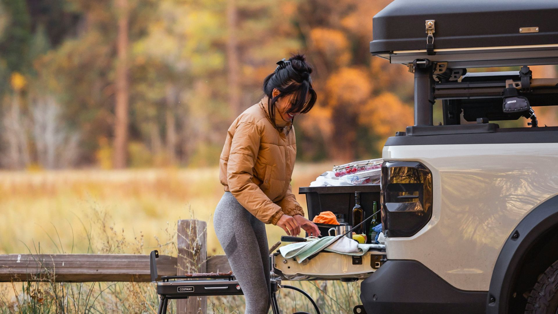 Woman cooking outdoors with a camper van
