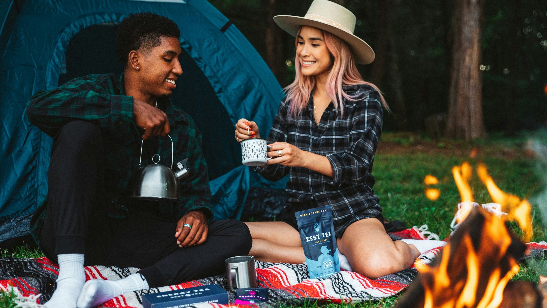 a man and a woman sitting next to a campfire