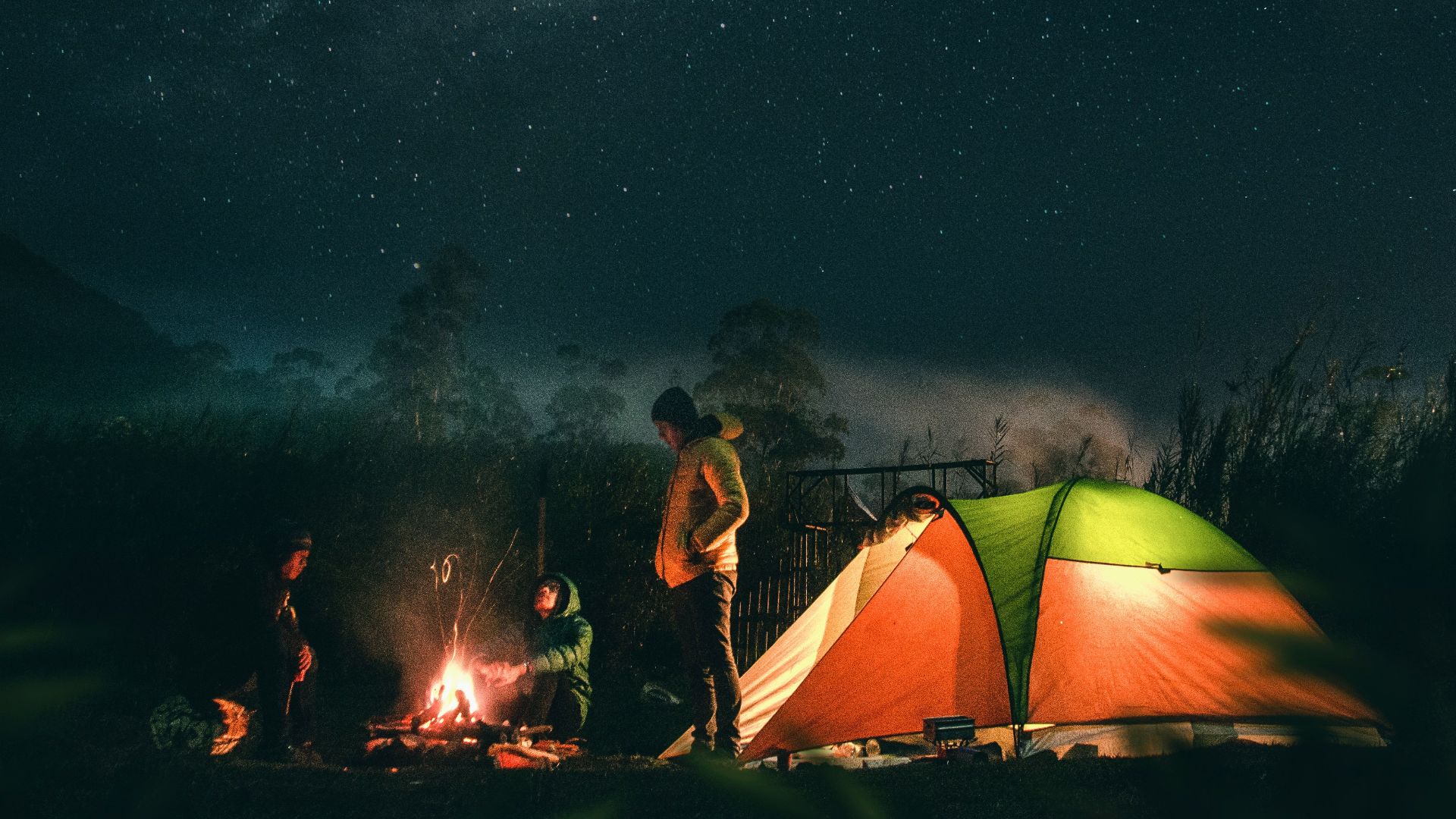 man in green and yellow tent under starry night