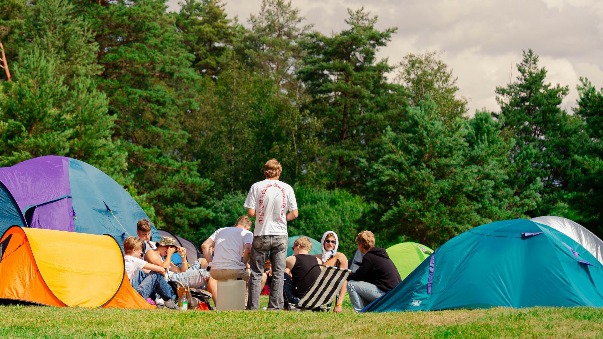 People are camping outside, gathered in a circle.