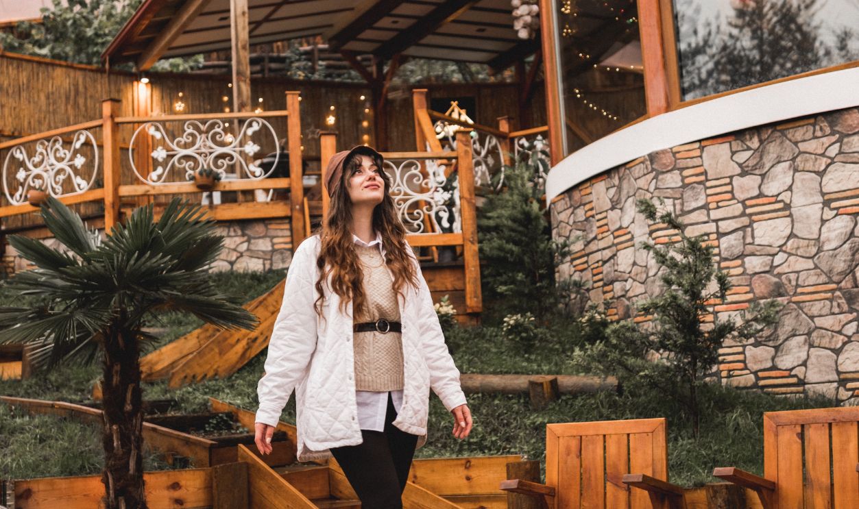 A woman standing by a pool in a wooden terrace during winter, embracing the tranquil environment