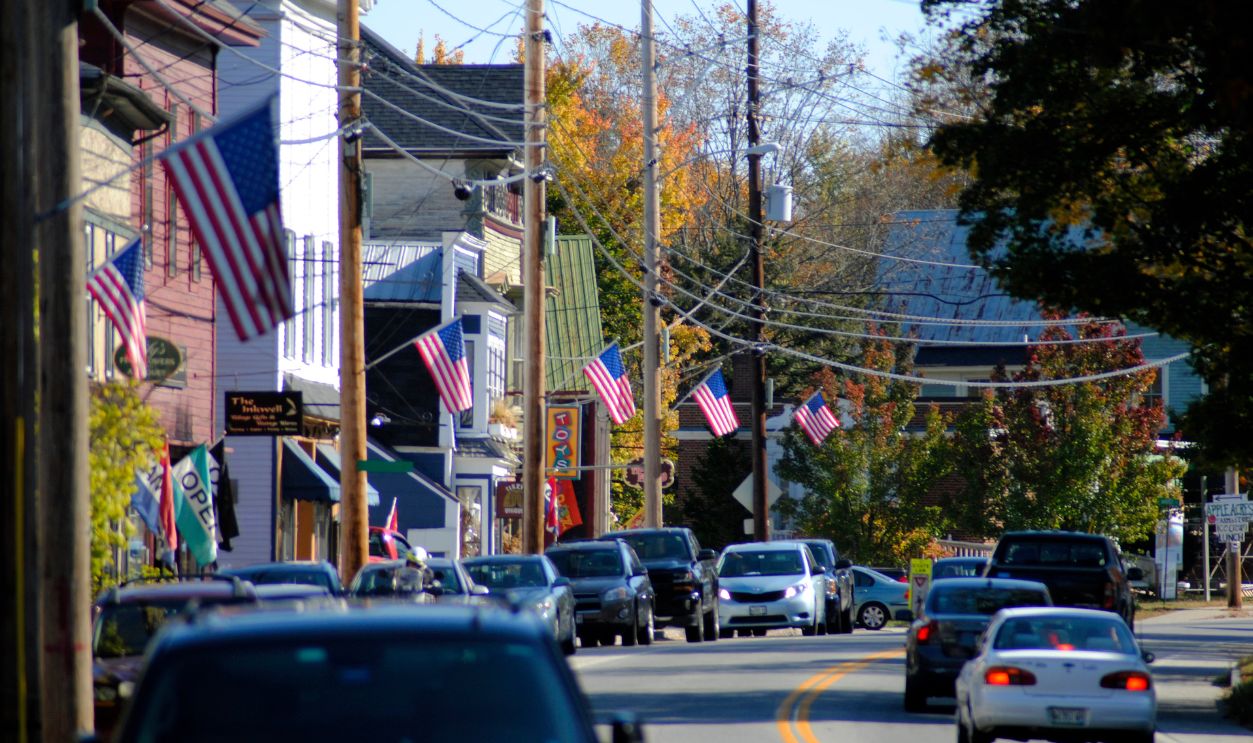 Charming town street lined with American flags and cars on an autumn day