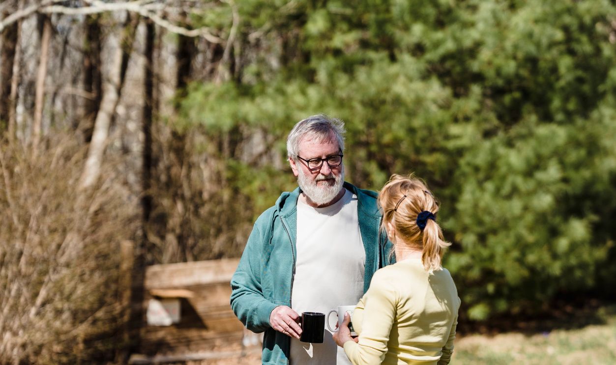 Senior couple bonding in a sunny garden, enjoying hot beverages and nature