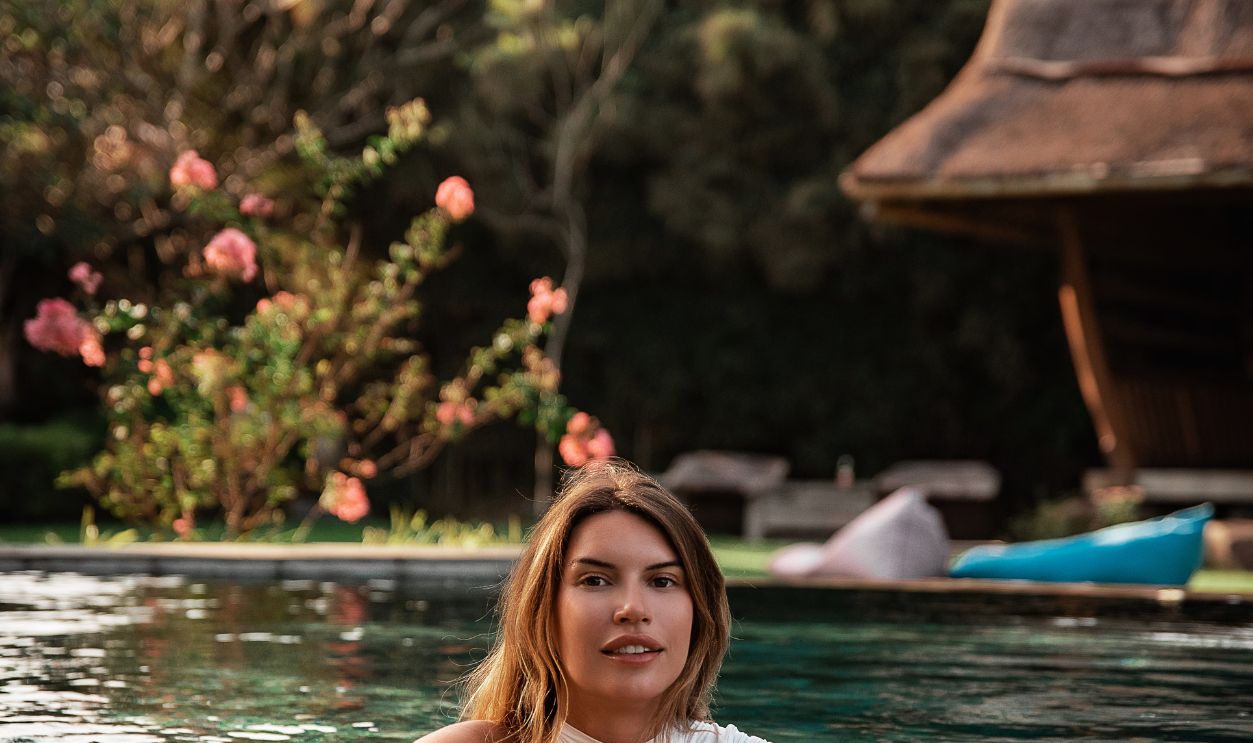 A woman enjoying a serene moment in an outdoor pool at a picturesque resort
