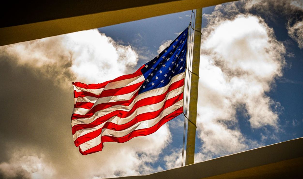 Dramatic view of the American flag waving on a bright day with clouds